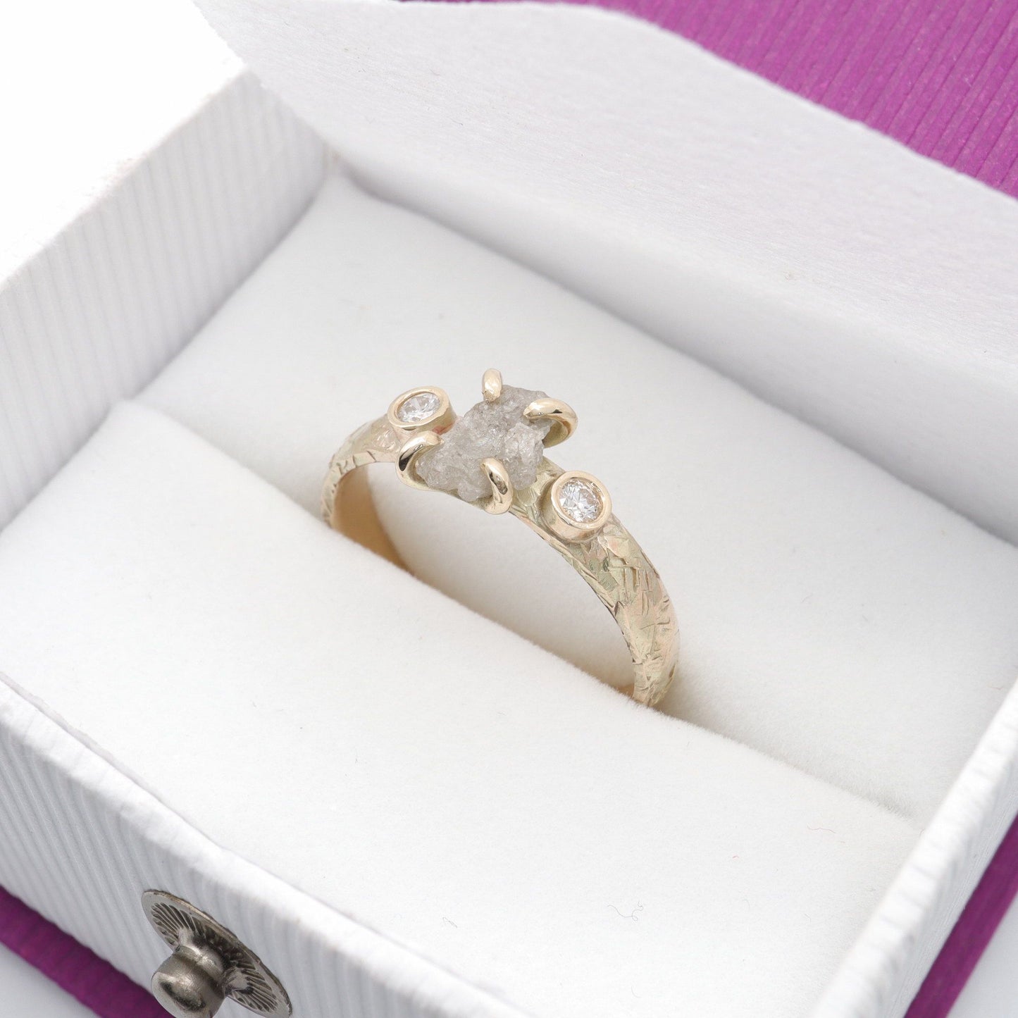 Diamond three stone gold ring set with raw uncut diamond.
